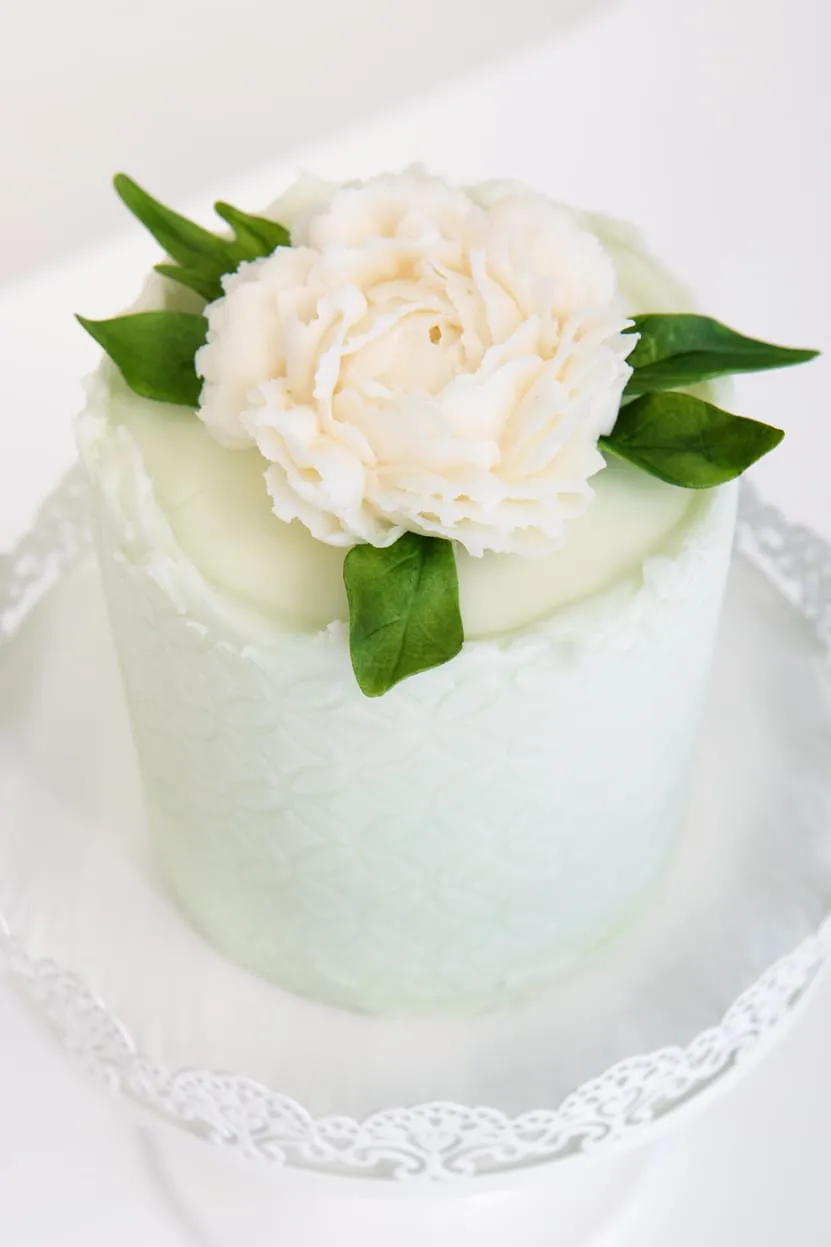 A small pale green cake with a white buttercream peony