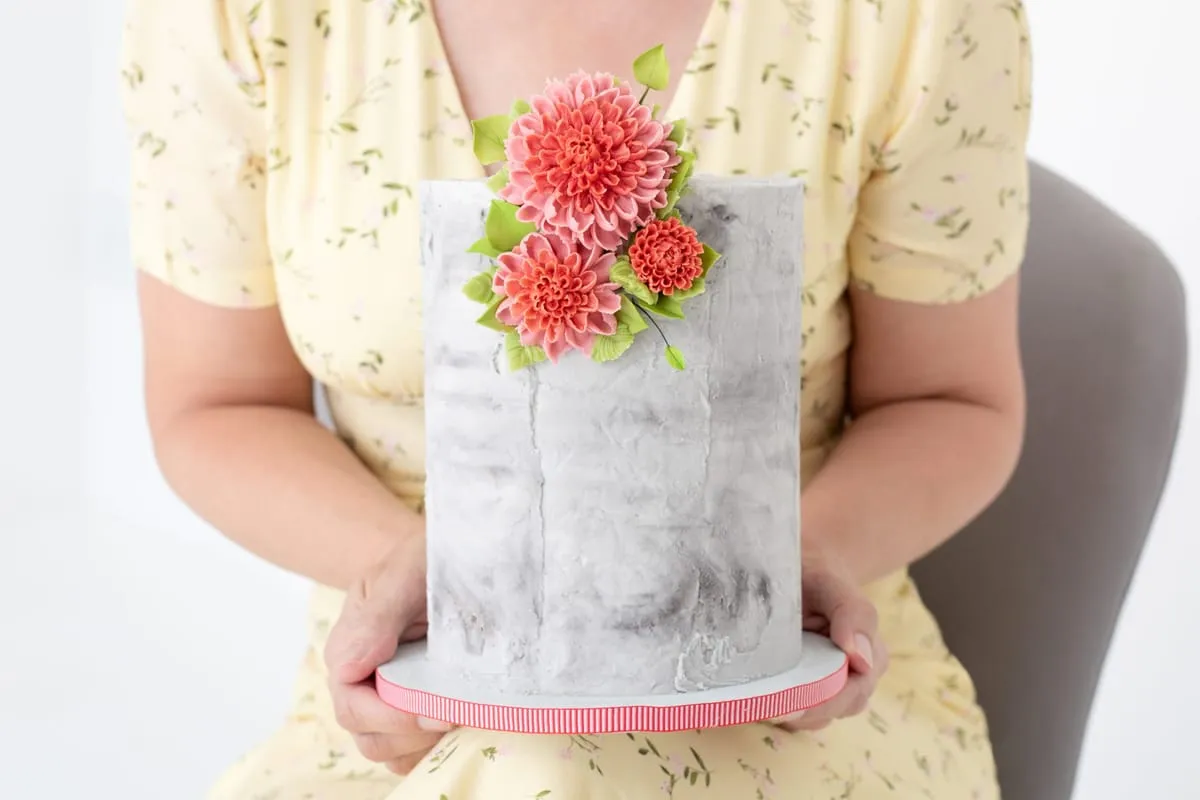 A grey marble cake with coral buttercream dahlias