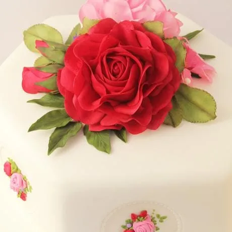 A large red sugar rose on a white hexagonal cake